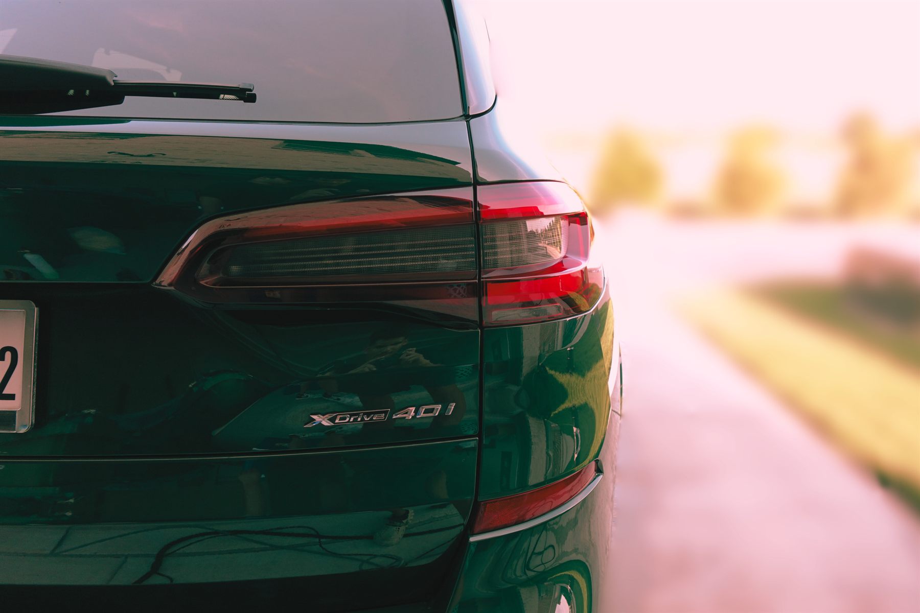 Deep green BMW X5 rear quarter panel with a mirror finish at golden hour